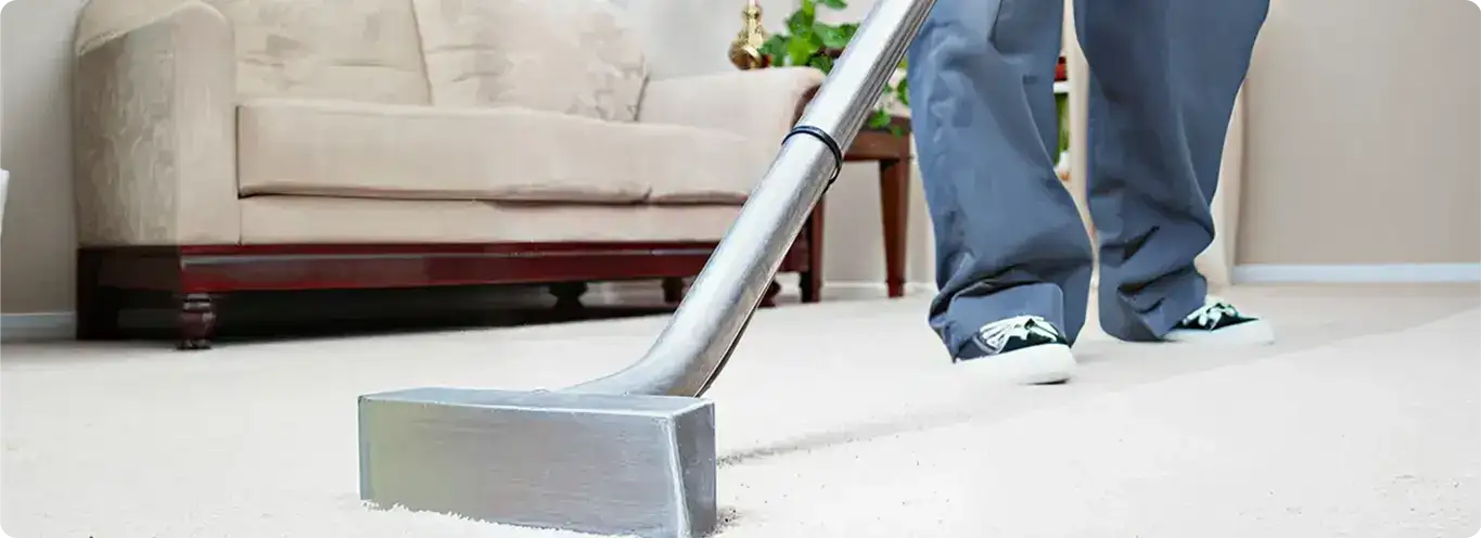 Carpet cleaning technician using a hot-water extraction wand on a light-colored carpet in a living room, Miami, FL.
