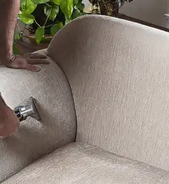 Professional upholstery cleaner deep-cleaning a fabric sofa with a handheld extraction tool and hose Miami, FL.